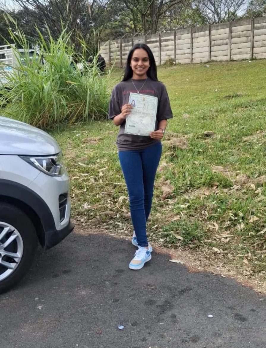 Smiling student holding her learner's licence outdoors