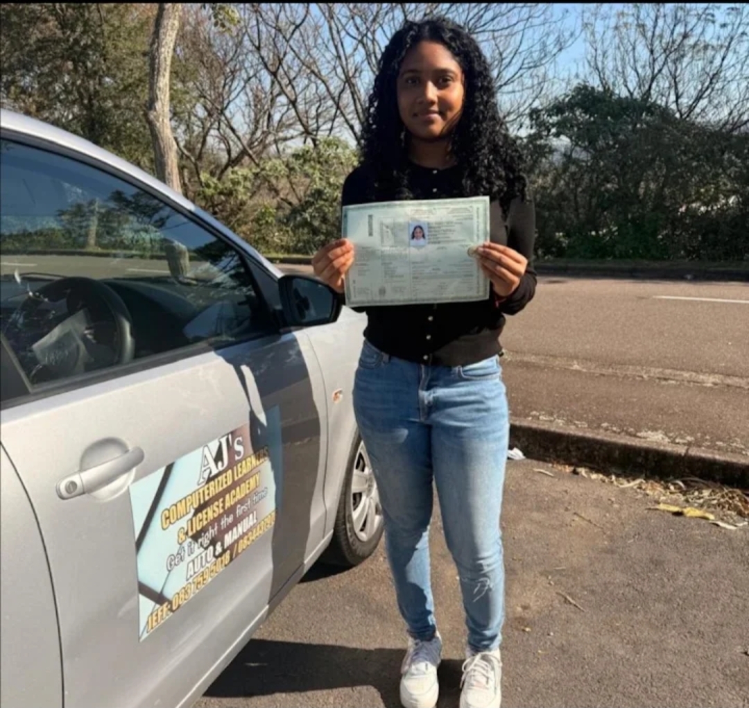 Student celebrating her licence next to the academy vehicle
