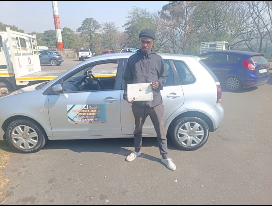 Student with his licence next to the academy's training car